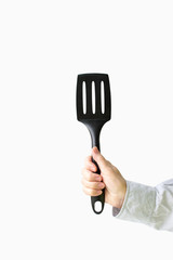 Black plastic spatula in female hands against white background