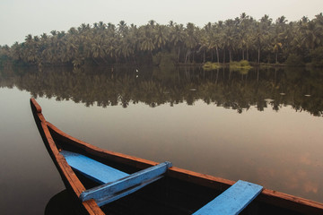 Wooden boat on the backwater canals on a background of tropical forest with palm trees. Copy, empty...