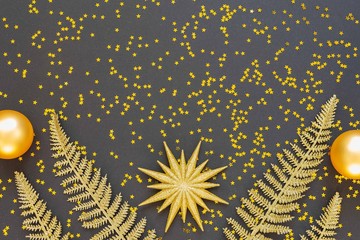 Festive background with gold decorations , shiny golden star and christmas balls on a black background with glitter gold stars , flat lay, top view, copy space