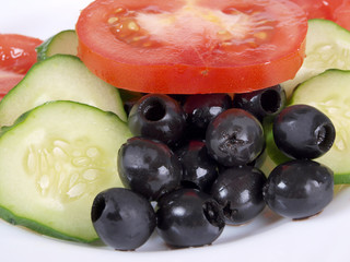 Salad of black olives, tomatoes and cucumbers on a porcelain plate