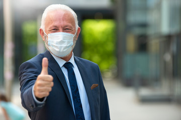 Portrait of senior business man with thumbs up