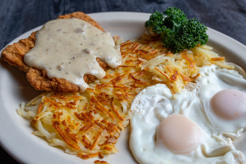 Country breakfast plate with chicken fried steak, hash browns and two over easy eggs