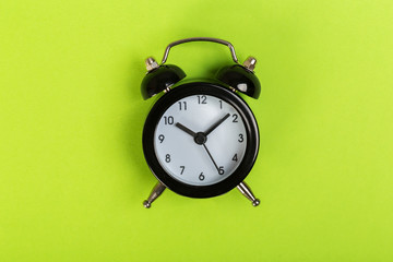 black vintage alarm clock on a colored background, top view. concept of time, daily routine