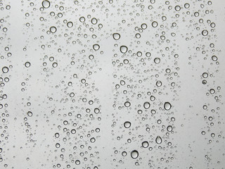 Raindrops on a transparent glass on a light background.