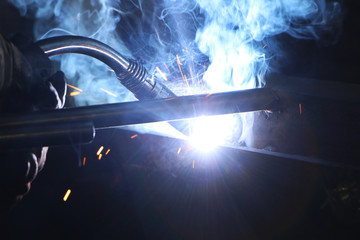 A highly skilled welder welds a metal structure at an assembly plant.