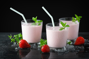Glass of fresh strawberry shake, smoothie or milkshake and fresh strawberries on table. Healthy food and drink concept with juicy fruits