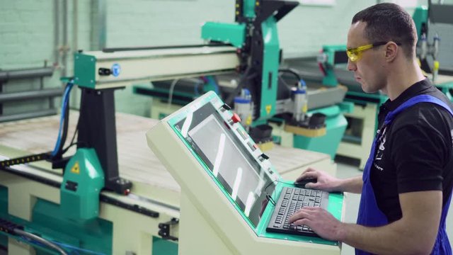 A male operator controls the CNC machine while standing at the control panel.