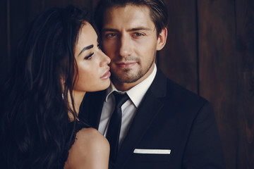 Elegant man in a black suit. Couple at home. Hot woman in a black underwear