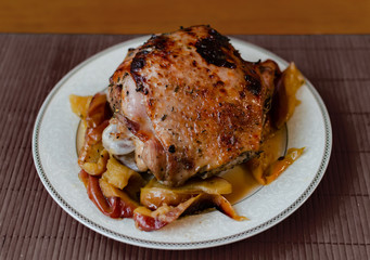 baked turkey thigh in apples on a large ceramic dish on a wooden table,