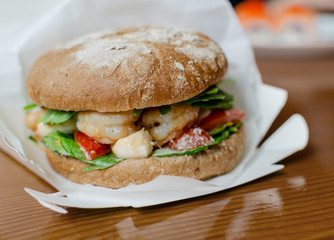 hamburger with dark flour with vegetables and shrimp on a wooden background