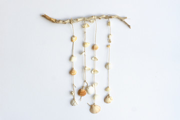 Handmade seashell mobile. Seashells hanging in the middle of a white background. Sea and summer decoration concept.