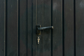 Metal black door with a black handle for background. Black metal door texture.