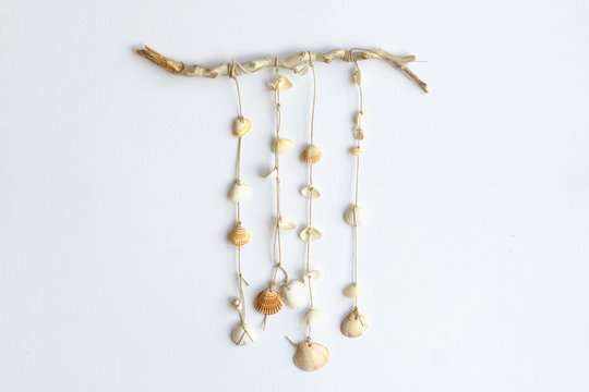 Handmade seashell mobile. Seashells hanging in the middle of a white background. Sea and summer decoration concept.