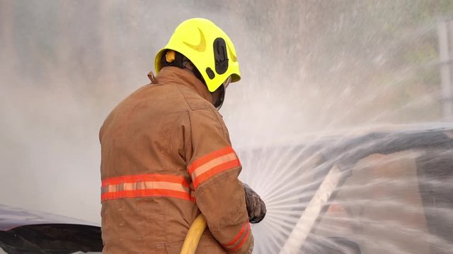 Slow motion/firefighters extinguishing the car caught on fire in a car accident