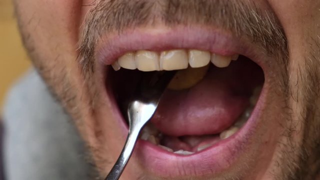 Bearded man eat tiny pancake cereal - trendy quarantine food. Close up person chews snack in slow motion.