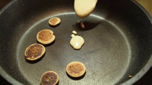 Process of cooking tiny pancake cereal - trendy quarantine food. Dough is poured into hot pan and mini pancakes are baked. Homemade breakfast.