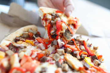 Male hand holding big piece of tasty fresh pizza