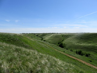 Landscape with a road among green hills against a blue sky