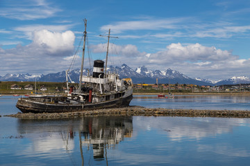 Fototapeta premium Old shipwreck in Ushuaia bay on sunny summer day with beautiful mountain view on background, Tierra del Fuego province, Argentina