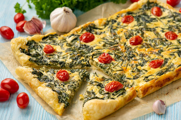Homemade spinach puff pastry tart with cheese and tomatoes.
