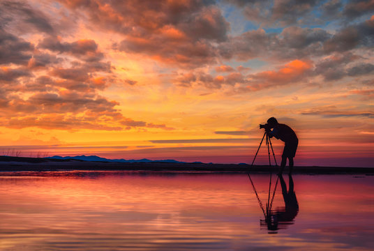 Silhouette Photographer take photo beautiful seascape at sunset in Thailand.