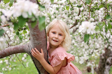 Cute Little Girl Child Playing OUtside in Spring Orchard on Apple Tree