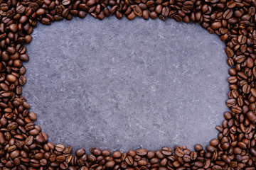 Frame made from roasted coffee beans over grey stone background with space for copy text