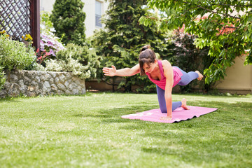 Young fit attractive brunette in Table posture. Backyard exterior.