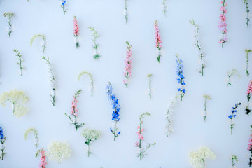 Flower multicolored installation. A lot of flowers of different colors fixed on a wall of white, blue, pink, yellow colors. Decoration of the walls. Vintage home decor background.