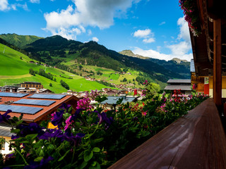Green hills of an alpine resort in Austria in summer. Small village, hotels and chalets, all in...