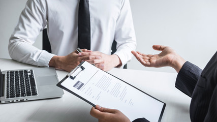 Employer or committee holding reading a resume with talking during about his profile of candidate, employer in suit is conducting a job interview, manager resource employment and recruitment concept