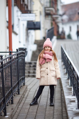 girl dressed in winter clothes walks along an old street