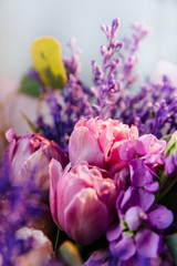 Obraz premium Stylish colorful floral bouquet with purple and pink tulips and roses. Designer flower bouquet from a florist. Beautiful blossoming flower wedding bouquet. Close up
