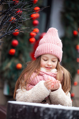 cute girl in winter clothes sculpts snowballs