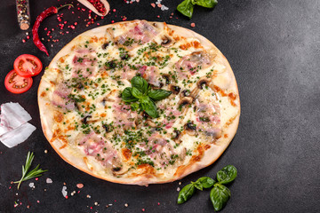 Fresh hot pizza with bacon, onions, greens and tomatoes made in an oven