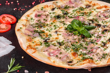 Fresh hot pizza with bacon, onions, greens and tomatoes made in an oven