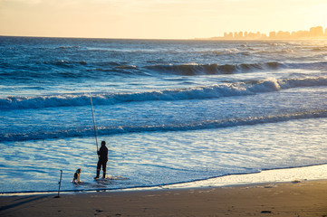 Fototapeta na wymiar man an his dog fishing n a beach