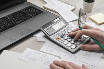 Man hand using calculator and writing make note with calculate about cost and taxes at home office. Businessman doing some paperwork in the workplace