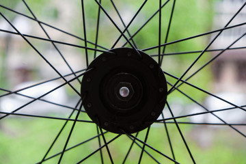 Part of the front bicycle wheel with spokes on a blurred  natural background. Copy space.