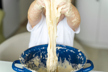 3-4 years old girl kneads yeast dough in a blue pan, hands closeup. family leisure