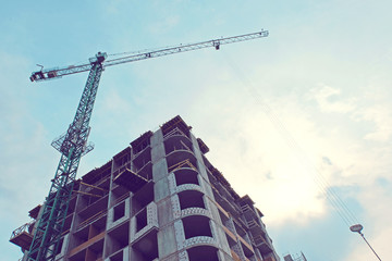 blue sunshine sky above building cranes at front of a multi-storey uilding under construction, new house for many families, babies and new life, building multi-storey building as symbol of hope to bet