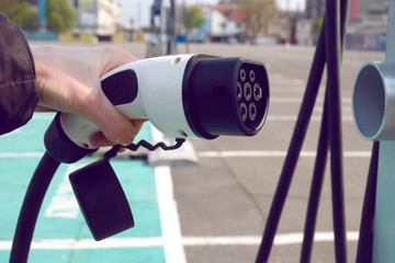 Power supply for electric car charging. Electric car charging station. Close up of the power supply plugged into an electric car being charged.