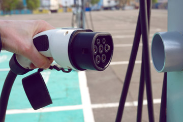 Power supply for electric car charging. Electric car charging station. Close up of the power supply plugged into an electric car being charged.