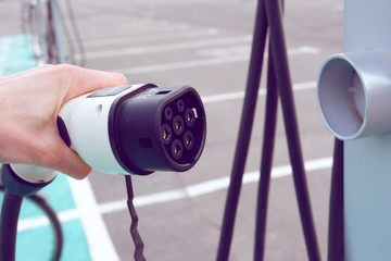 Power supply for electric car charging. Electric car charging station. Close up of the power supply plugged into an electric car being charged.