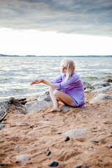 Fototapeta na wymiar blonde girl sitting on the beach and pouring sand