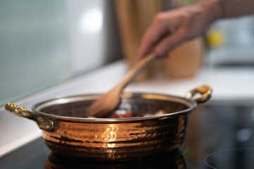 vintage textured copper cooking pot on kithcen with male hand cooking mixing food in pot