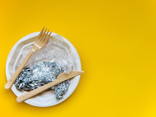 Disposable plastic appliances and a plate on a yellow background. Concept of environmental pollution. Flat lay, copy space