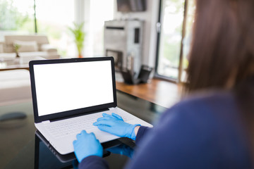 Freelancer working on empty screen laptop from home and wearing protective gloves, covid-19 concept.