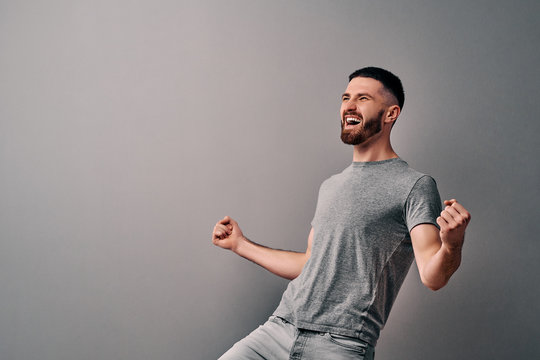 Portrait Of Emotional Handsome Guy Gesturing Victory Sign On Gray Background!Victory, Happy And Goal Scream Emotions Fan Concept. Copy Space.