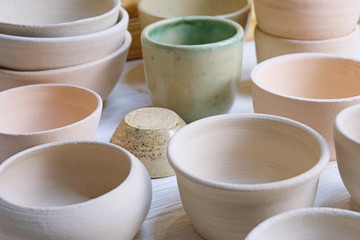 Modern pottery. Decorative ceramic, clay plate. Handmade light pottery.  Set of ceramic, bowls, cup with background.